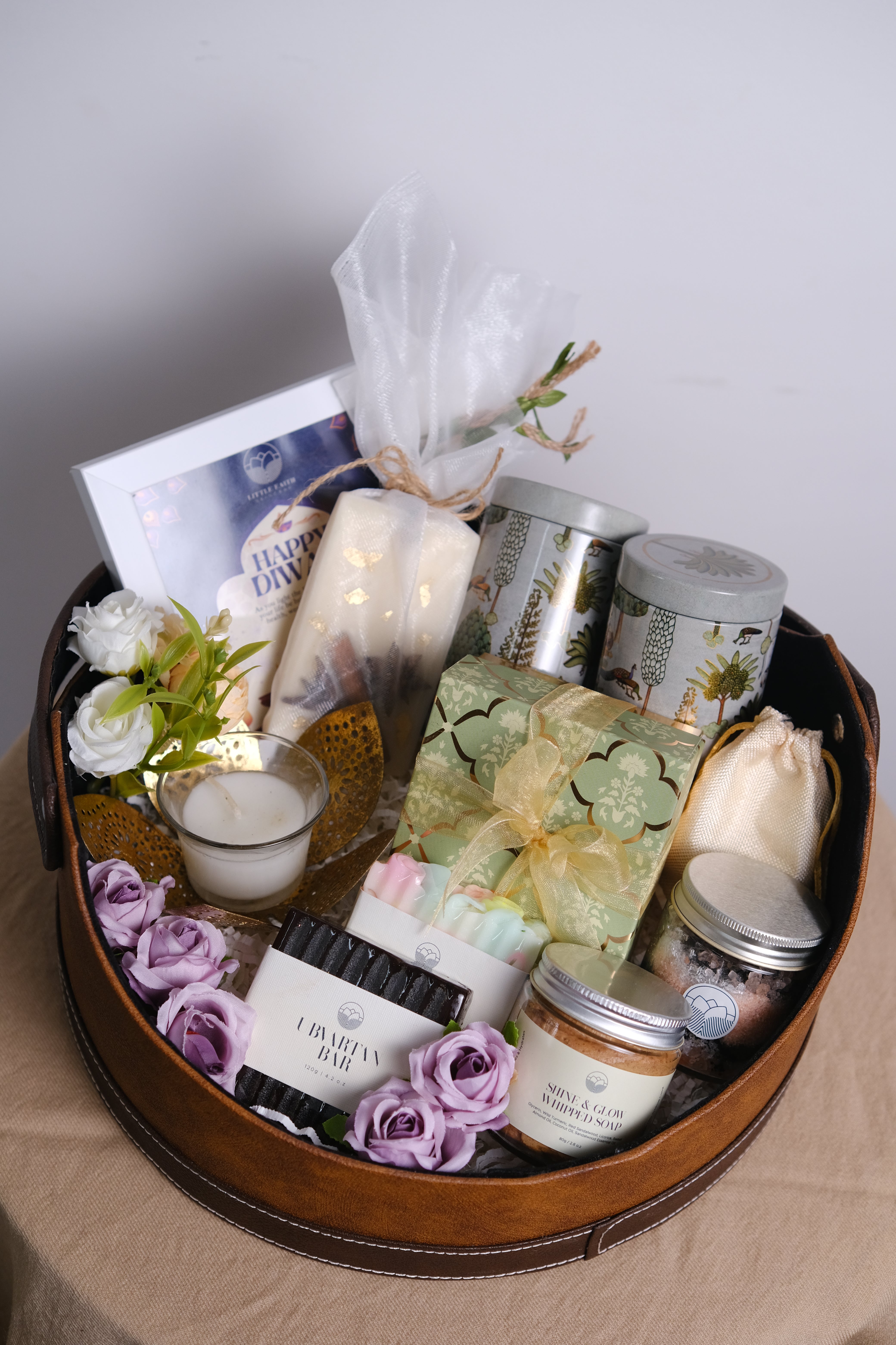 Gift basket with candles, flowers, and other items on a light surface